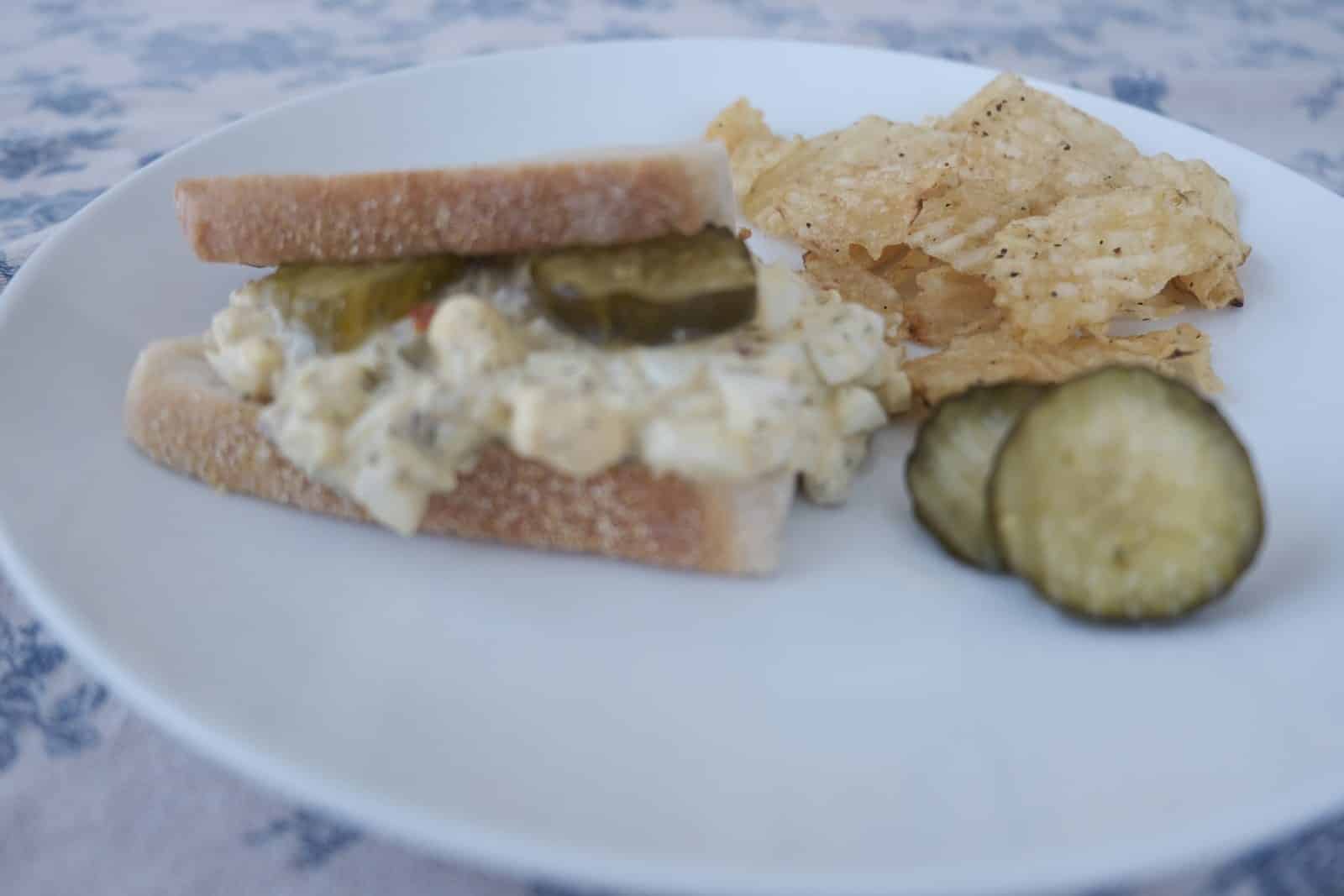 Egg salad sandwich with pickles and chips